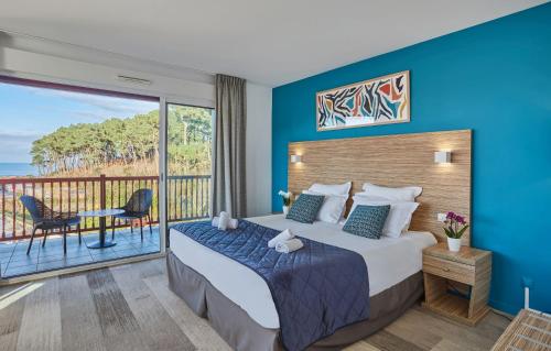 a bedroom with a large bed and a balcony at Hôtel Prestige Odalys Erromardie in Saint-Jean-de-Luz