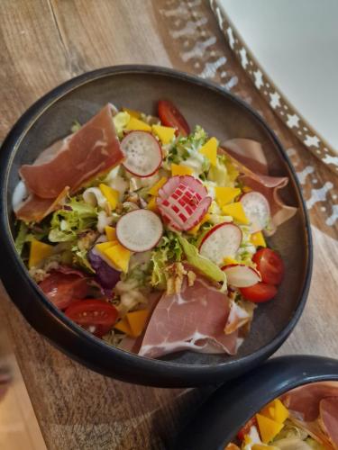 a bowl of salad with meat and vegetables on a table at Lodge tente les pommiers Glamping Ô rendez-vous en demi-pension in Roquefeuil