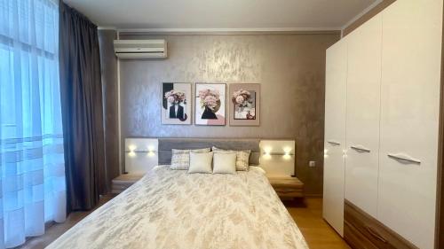 1 dormitorio con 1 cama grande y 3 cuadros en la pared en Bratanov Flower Street Apartment, en Sunny Beach