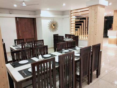 a dining room with a table and wooden chairs at Vibes Selaqui Hotel Dehradun in Dehradun