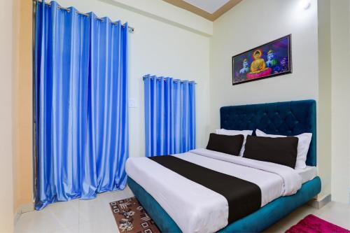 Hotel Maujis Inn في Prayagraj: غرفة نوم بسرير كبير مع ستائر زرقاء