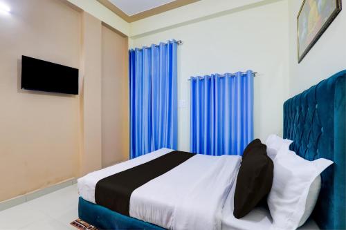 Hotel Maujis Inn في Prayagraj: غرفة نوم بسرير والستائر زرقاء