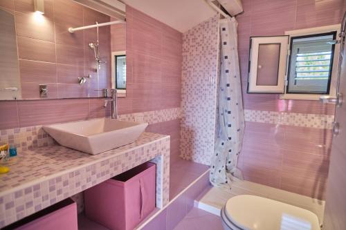 un bagno rosa con lavandino e servizi igienici di Villa Sicilia a Lascari