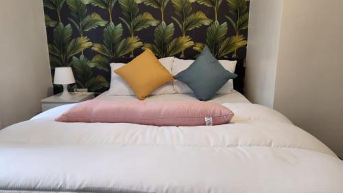 een bed met een stapel kussens erop bij Charming 2-Bedroom Home with Modern Amenities in Oldham