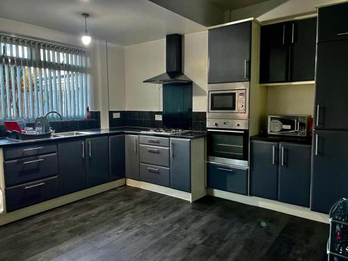 een keuken met donkerblauwe kasten en apparatuur bij Charming 2-Bedroom Home with Modern Amenities in Oldham