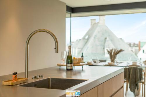 a kitchen with a sink and a bottle of wine at Rêve des Dunes – luxury apartment by the sea in Koksijde