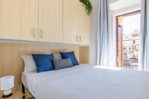 una camera da letto con un grande letto bianco con cuscini blu di Maison Blu - in Trastevere a Roma