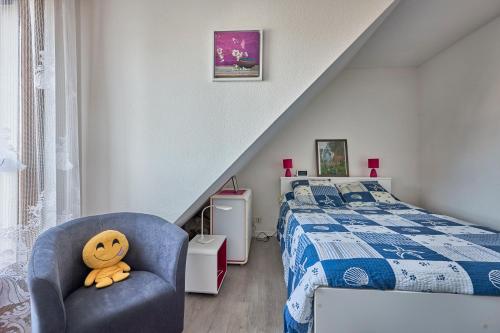 - une chambre avec un lit et une chaise avec un ours en peluche dans l'établissement Doudounette - Appartement à proximité de la plage, à Courseulles-sur-Mer