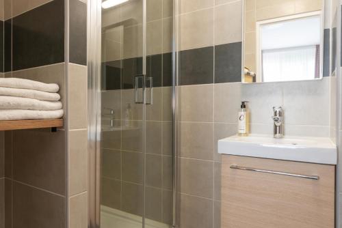 La salle de bains est pourvue d'une douche et d'un lavabo. dans l'établissement The Originals City, Hôtel Notre Dame, Rouen, à Rouen