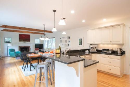 a kitchen with white cabinets and a table with bar stools at Perfectly private location w deeded beach access in Orleans