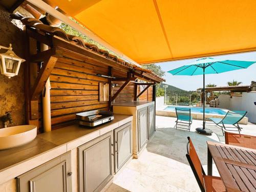 une cuisine extérieure avec un parasol et une piscine dans l'établissement Mazet de la Treille, climatisé avec piscine privée pour 4 pers Domaine privé, à La Londe-les-Maures