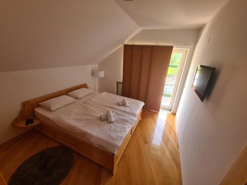 a bedroom with a bed with white sheets and a window at Zaprešić apartmani i sobe in Zaprešić