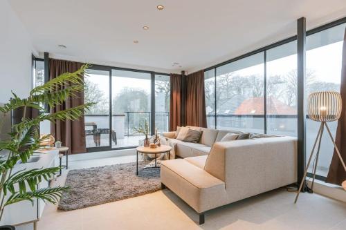een woonkamer met een bank en een aantal ramen bij Apartment with two large terraces in Zedelgem