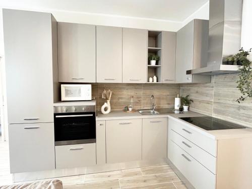 a white kitchen with white cabinets and a microwave at Quick Home - Orchidea in Biella