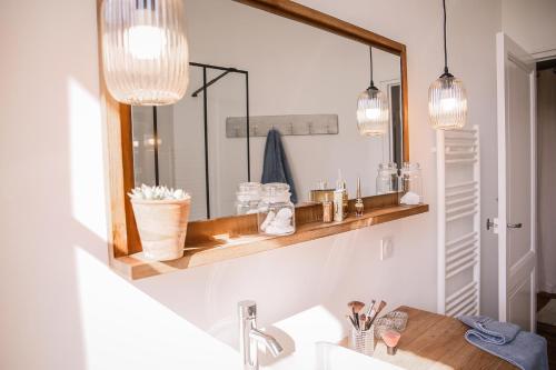 een badkamer met een wastafel en een spiegel met verlichting bij Maison 15 in Sauternes