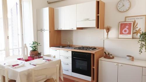 a kitchen with white cabinets and a table and a stove at Quick Home - Appartamento Narciso in Biella