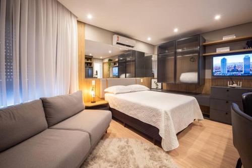 a bedroom with a bed and a couch and a television at Loft 410 vista Parque Una in Pelotas