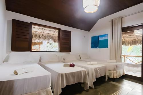 um quarto com três mesas brancas e uma janela em Bangalô da Barra, chalé 20 - BG em Barra Grande
