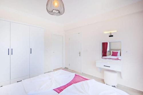 a white bedroom with a bed and a mirror at Villa Simge 4+1 Ölüdeniz in Fethiye