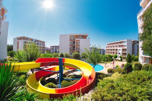 a colorful water slide in a park with buildings at Imperial and Crown Fort Noks Grand Resort in Sveti Vlas