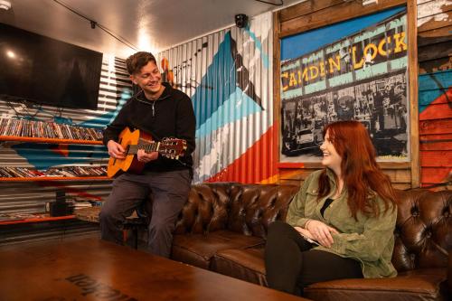 a man playing a guitar and a woman sitting on a couch at Urban Nomad - Camden Town in London