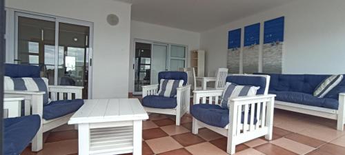 a living room with blue and white chairs and a table at Vista Bonita Apartments in Mossel Bay