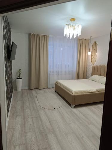 1 dormitorio con cama y lámpara de araña en 1-комнатная квартира мкр. Аэропорт en Kostanái
