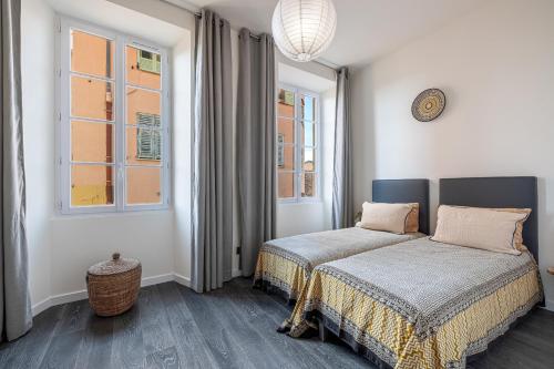 une chambre avec deux lits et deux fenêtres dans l'établissement Le Bréa, Élégant appartement, jolie vue mer, à Menton