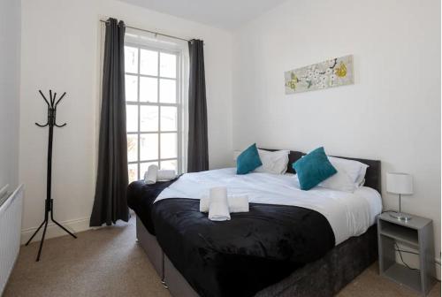 een slaapkamer met een groot bed met blauwe kussens bij Devonshire Road - Apartment 1 in Birkenhead