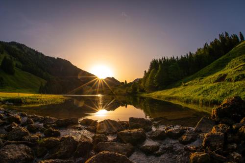 a sunset over a river with rocks in the foreground at Zu Gast bei den Hagspiels in Hittisau