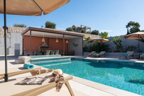 a pool with chairs and an umbrella next to a house at Elias' Rest in Pastida