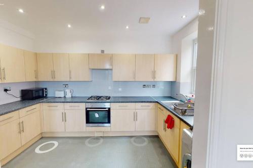 a kitchen with white cabinets and a stove top oven at Huge Flat Sleeps 6+ free parking in Nottingham