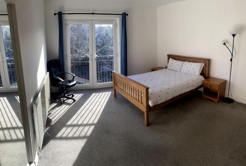 ein Schlafzimmer mit einem Bett in einem Zimmer mit Fenstern in der Unterkunft Huge Flat Sleeps 6+ free parking in Nottingham