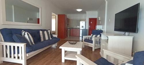 a living room with a blue couch and a tv at Vista Bonita Apartments in Mossel Bay