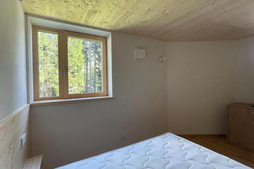 an empty room with a bed and a window at Chalet immerso nel verde in Madesimo