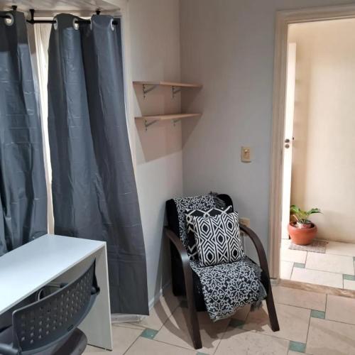 einen Stuhl in einem Zimmer mit einem Schreibtisch und einem Fenster in der Unterkunft dormitorio 01 privativo a 2 km de alphaville in Barueri