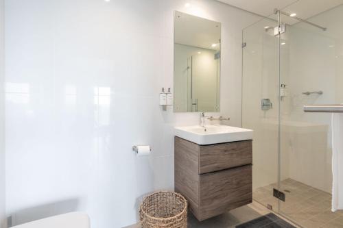 a white bathroom with a sink and a shower at Oceans Umhlanga Accommodation in Durban