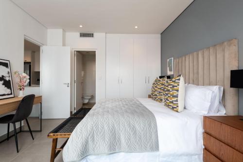 a bedroom with a white bed and a desk and a desk at Oceans Umhlanga Accommodation in Durban