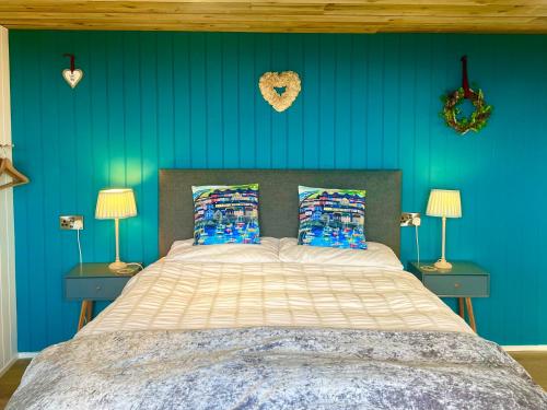 1 dormitorio con 1 cama con paredes azules y 2 lámparas en The Pod & Cwtch luxury accommodation en Aberaeron