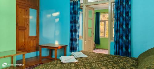 1 dormitorio con paredes azules, 1 cama y 1 mesa en Jagatram Niwas en Dharamshala
