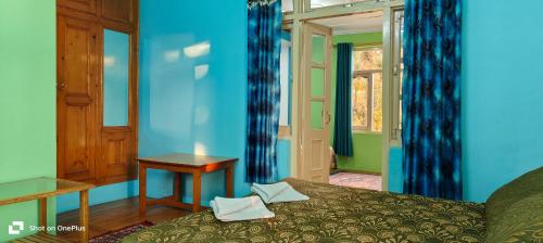 a bedroom with blue walls and a bed and a table at Jagatram Niwas in Dharamshala