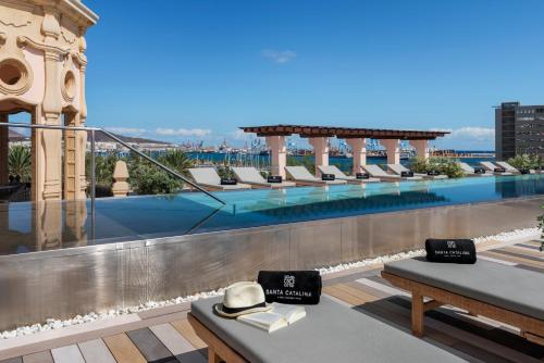 a hotel rooftop with a swimming pool and chairs at Santa Catalina, a Royal Hideaway Hotel in Las Palmas de Gran Canaria
