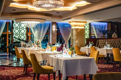 a restaurant with white tables and chairs and a chandelier at Wellness & Spa Hotel Kaskady in Sliač