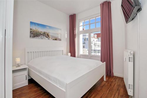 a white bedroom with a bed and a window at Haus am Park Wohnung 32 in Kühlungsborn