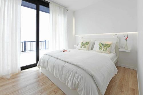 Casa Piccola Stella في تيخارافي: غرفة نوم بيضاء مع سرير كبير ونافذة كبيرة