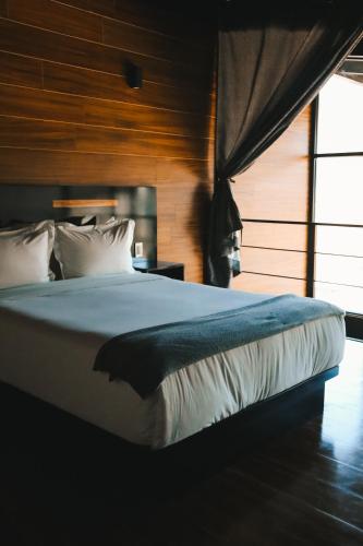 a bedroom with a bed and a large window at Origen75 Loft - Villas - Skypool - Viñedo, Valle de Guadalupe in Valle de Guadalupe