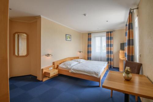 a hotel room with a bed and a table at Hotel Reiff in Fischbach-lès-Clervaux