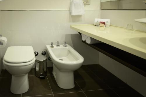 a white bathroom with a toilet and a sink at Mérit San Telmo in Buenos Aires