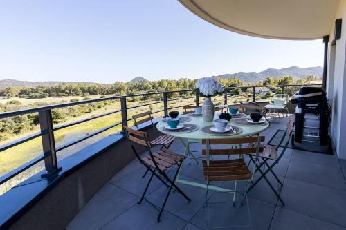 une table et des chaises sur un balcon avec vue dans l'établissement Le Gaston - Appartement vue dégagée Porto Vecchio, à Porto-Vecchio
