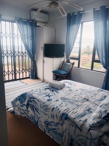 a bedroom with a bed and a chair and windows at Bayview Guest House in Amanzimtoti